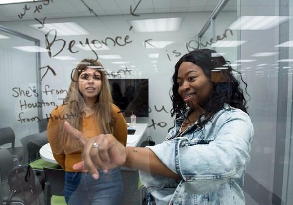 Two women looking at writing on glass